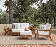 an outdoor seating area with two chairs and a coffee table on top of a brick patio