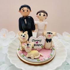 a wedding cake topper with two dogs and a bride and groom standing on it