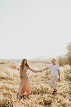 a man and woman holding hands in a field