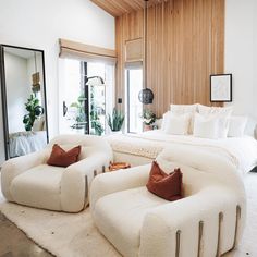 a large white bed sitting in a bedroom on top of a floor next to a mirror