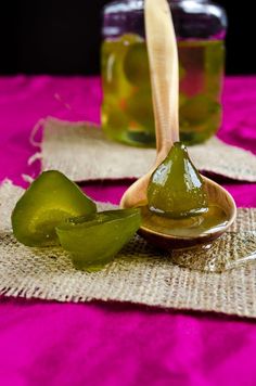 two spoons filled with green liquid sitting on top of a pink cloth covered table