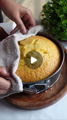 a person wiping down a cake in a pan on top of a wooden platter