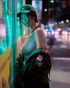 a woman standing next to a wall with a green light on it's side