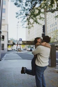 two people hugging each other on the street