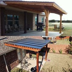 an outdoor patio with a grill and table next to it on the grass near a brick building