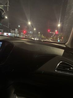 the dashboard of a car at night with street lights in the background and cars driving down the road