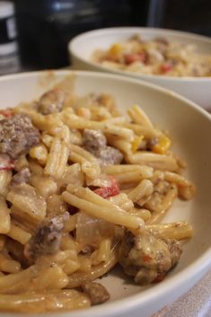 two bowls filled with pasta and meat on top of a table