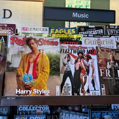 magazines are stacked on top of each other in front of a store sign and billboard