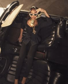 a woman sitting in the back of a car with her hands on her head and wearing sunglasses