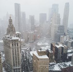 the city is covered in snow as it sits on top of tall buildings and skyscrapers