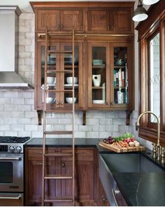 a kitchen with wooden cabinets and ladders in the center, along with black counter tops