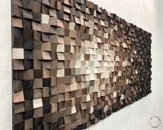 a wall sculpture made out of wooden blocks on the side of a white walled wall