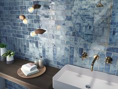 a bathroom with blue tiles on the wall and wooden countertop, along with a white sink