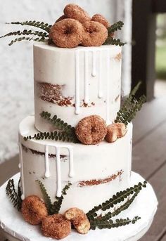 a three tiered cake with donuts on top and ferns in the bottom layer