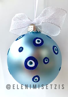 a blue ornament with an evil eyeball on it and a white bow