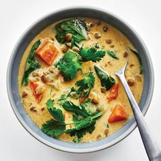 a bowl filled with soup and topped with green leafy garnish, next to a spoon