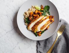 a white plate topped with chicken, rice and veggies next to a fork