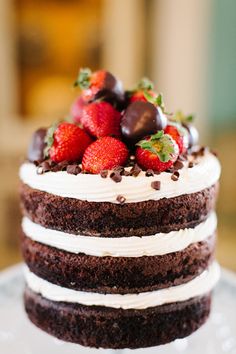 a chocolate cake with white frosting and strawberries on top