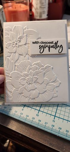 a close up of a person holding a card with flowers on it and the words, with deepest sympathy