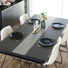 a dining table with black plates and white chairs