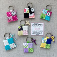 several small pieces of fabric hanging from key chains on a table with a note attached to them