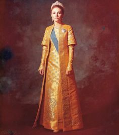 an old fashion photo of a woman in gold and blue dress, standing against a red background