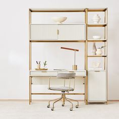 a desk with a chair, lamp and vases on the shelves in front of it