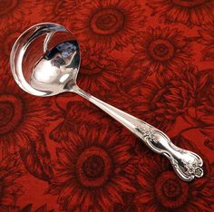 a silver spoon sitting on top of a red tablecloth covered with sunflowers