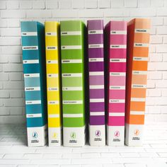 five different colored books lined up against a white brick wall in front of each other