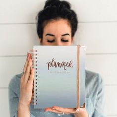 a woman holding up a notebook with the word pommee written on it in front of her face