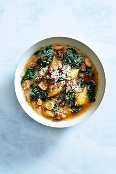 a white bowl filled with food on top of a blue table next to a wooden spoon