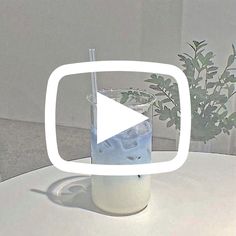 a glass filled with water sitting on top of a white table next to a potted plant