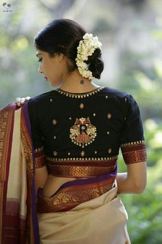 a woman wearing a black and white sari with flowers in her hair is looking down