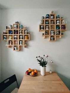 two wooden shelves on the wall above a table with fruit and flowers in vases