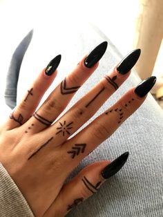 a woman's hand with black nail polish and tattoos on her fingers, holding a knife