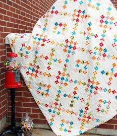 a quilt is hanging on the side of a brick wall next to a red fire hydrant