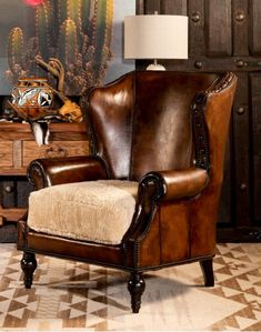 a brown leather chair sitting in front of a wooden table with a lamp on top of it