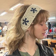 a woman wearing a white knitted headband with blue flowers on the front and side