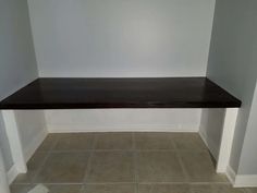 an empty room with tile flooring and a shelf on the wall in front of it