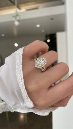 a woman's hand with a ring on top of her finger and white gloves