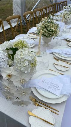 the table is set with white flowers and place settings for guests to sit down at