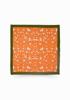 an orange and green placemat with white flowers on the border, in front of a white background