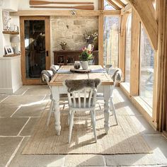 the interior of a house with wooden beams and windows, including a table and chairs