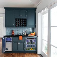 a kitchen with dark green cabinets and wood flooring is pictured in this image, there are several bottles on the counter