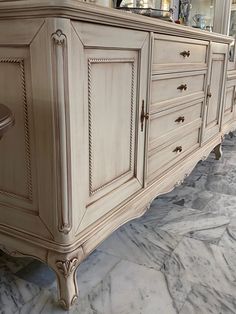 a large white dresser sitting on top of a marble floor