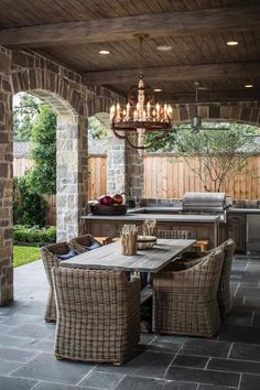 an outdoor dining area with wicker furniture and chandelier hanging from the ceiling