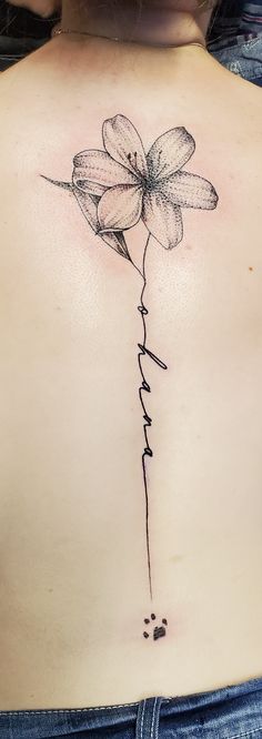 a woman's back with a flower tattoo on her left side ribcage