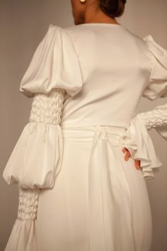 the back of a woman's white dress with ruffled sleeves