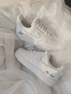 a pair of white nike air force sneakers on top of a bed covered in tulle