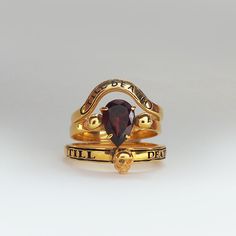 two gold rings with a garnet stone on each one and an inscription that reads, i will be dead